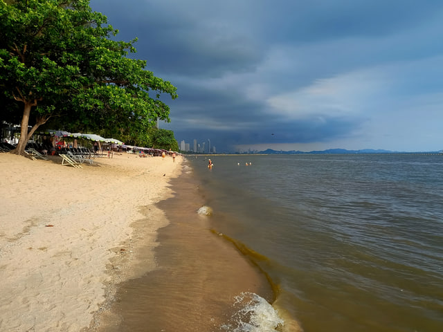 Archive photograph: Dongtan Beach with trees, beach chairs, sand and the shoreline beneath a cloudy sky